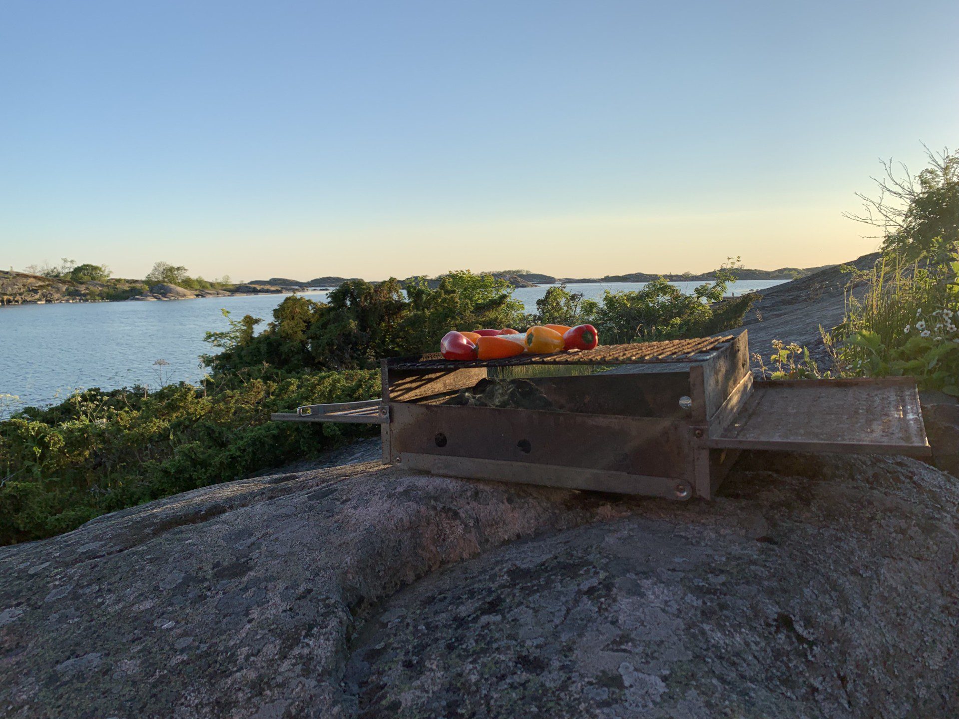 Guests enjoying a sunset BBQ on smooth granite rocks at Fredlarna island in the Stockholm Archipelago.