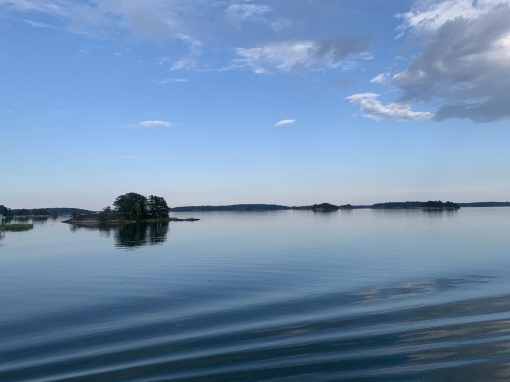 Skärgårdsupplevelser med RIB‑båt i Stockholms skärgård Calm blue waters and small wooded islands in the Stockholm archipelago, showcasing the natural scenery experienced on RIB speedboat charters with 59 Degrees North
