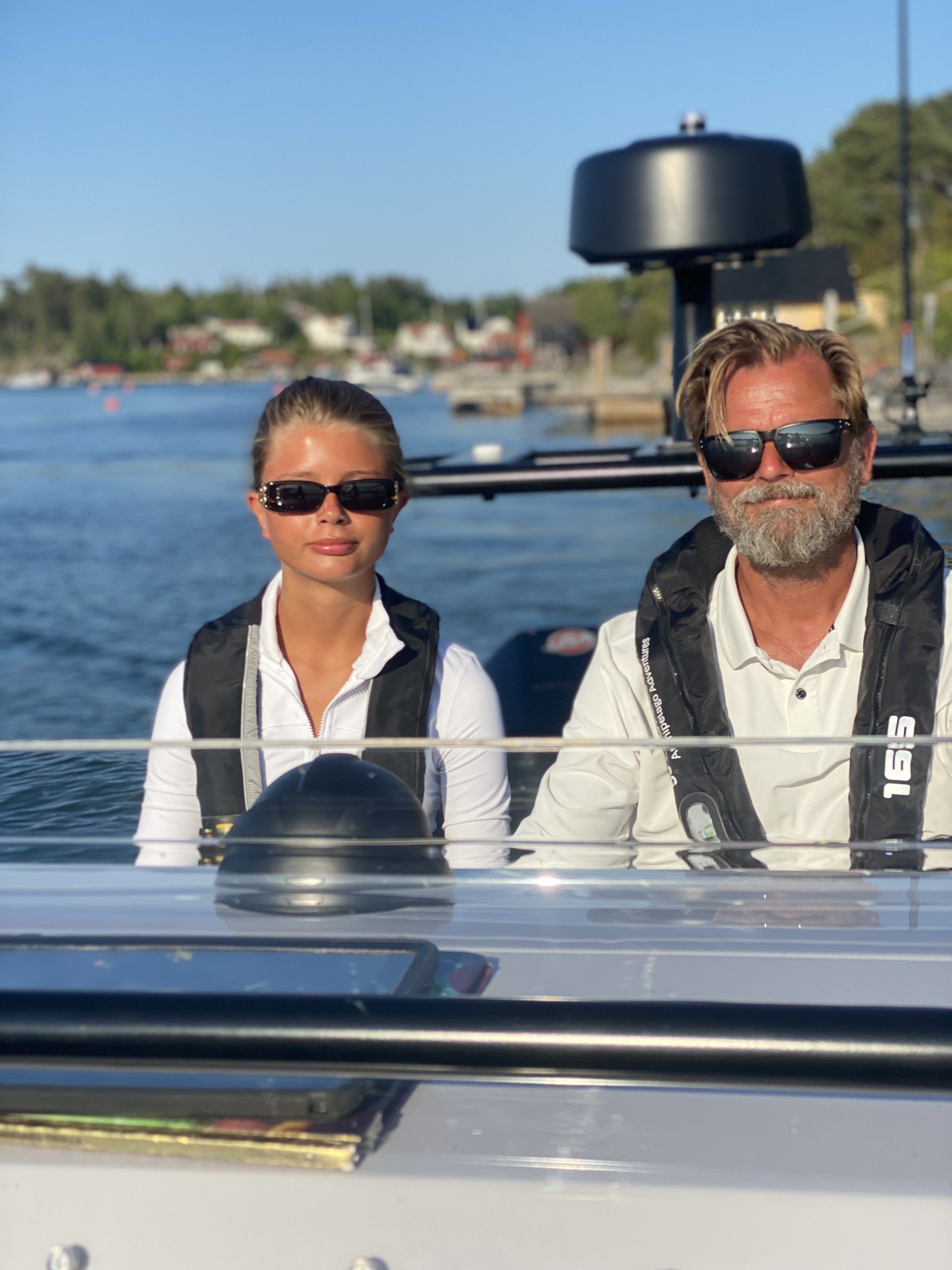 Lokala experter på RIB‑upplevelser i Stockholms skärgård Summertime in the archipelago - The crew seated on a RIB boat in the Stockholm archipelago, wearing safety vests and sunglasses, during a private RIB charter with 59 DEGREES NORTH.